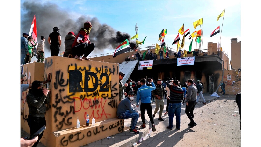 FILE - Pro-Iranian militiamen and their supporters light a fire during a protest in front of the U.S. Embassy in Baghdad, Iraq, Jan. 1, 2020.