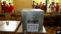 FILE - Young men are seen taking photos of a ballot box at a polling station in Phnom Penh, Cambodia, July 28, 2013.