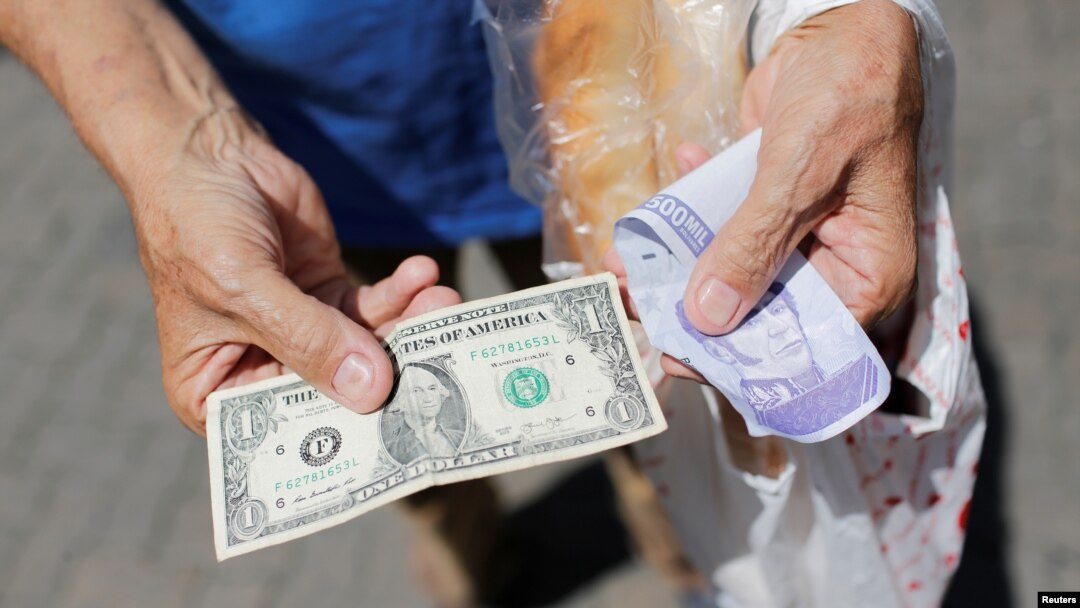 Un vendedor ambulante sostiene un billete de un dólar junto a un viejo billete de Bolívar en Caracas. Octubre 1, 2021.