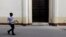 FILE - A woman walks past closed doors at the Church of Our Virgin of Charity in Havana March 14, 2012.