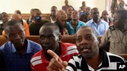 FILE - Cult preacher Pastor Paul Nthenge Mackenzie of the Good News International church, foreground right, and some of his helpers sit at the Shanzu Law Courts under tight security, in Mombasa, Kenya Thursday Aug. 10, 2023 during a bail hearing.