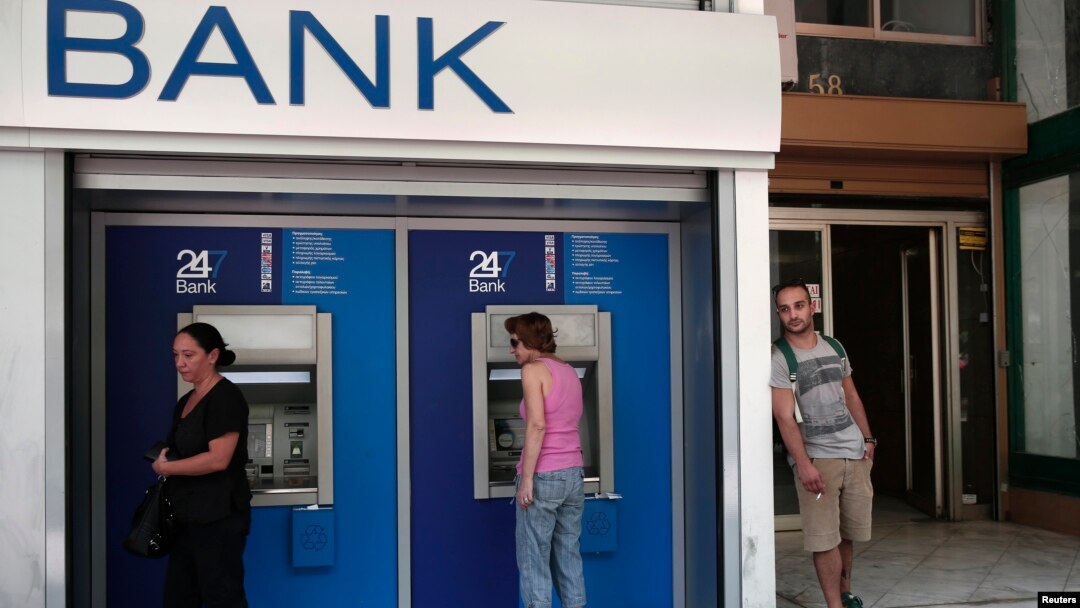People make transactions at ATM machines outside a bank branch in Athens, Aug. 12, 2013.