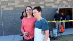 Alicia Willis walks away with her son at a high school where people were evacuated after a shooting at the nearby Rigby Middle School, May 6, 2021, in Rigby, Idaho.