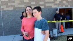 Alicia Willis walks away with her son at a high school where people were evacuated after a shooting at the nearby Rigby Middle School, May 6, 2021, in Rigby, Idaho.