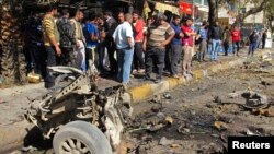 Residents are seen inspecting the site of a car bomb attack in the Karrada district in Baghdad February 17, 2013.