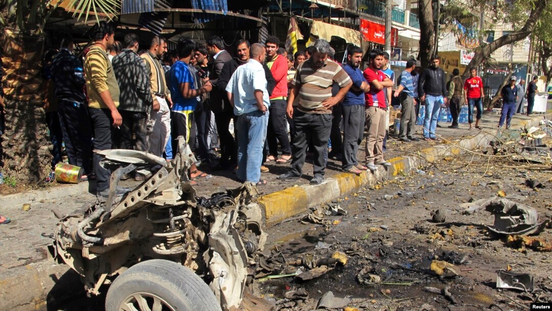 Warga Irak memeriksa lokasi ledakan bom mobil di kawasan warga Syiah di distrik Karrada, Baghdad hari Minggu (17/2). 