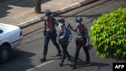 FILE - Police arrest a Myanmar Now journalist in Yangon, Feb. 27, 2021, as protesters were taking part in a demonstration against the military coup.