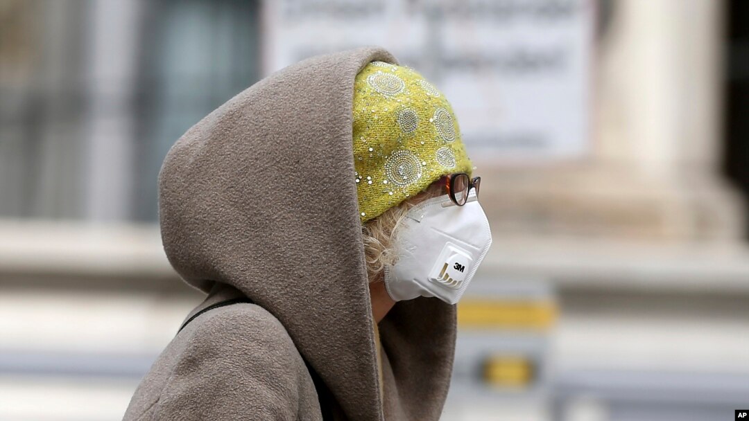 Seorang perempuan meggunan masker di Wina, Austria, 30 Maret 2020. (Foto: AP)