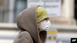 Seorang perempuan meggunan masker di Wina, Austria, 30 Maret 2020. (Foto: AP)