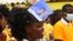 Une femme portant un tract de campagne électorale du Président sortant Patrice Talon et de sa colistière Mariam Talata participe à un meeting de campagne à Abomey-Calavi, le 9 avril 2021.
