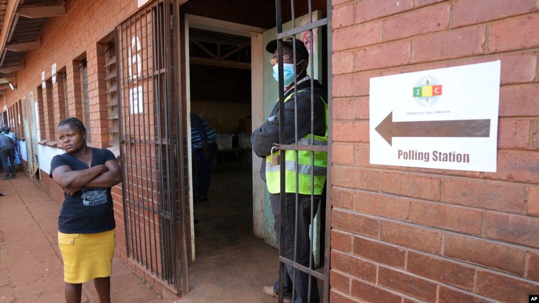 A woman waits outside a polling station in Harare, Wednesday, Aug. 23 2023.