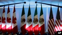 FILE - National flags representing Canada, Mexico, and the U.S. are lit by stage lights at the North American Free Trade Agreement, NAFTA, renegotiations, in Mexico City, Sept. 5, 2017. 