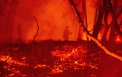 FILE - Firefighters work the scene at a burning property during the Glass fire in Calistoga, California, Oct. 1, 2020.