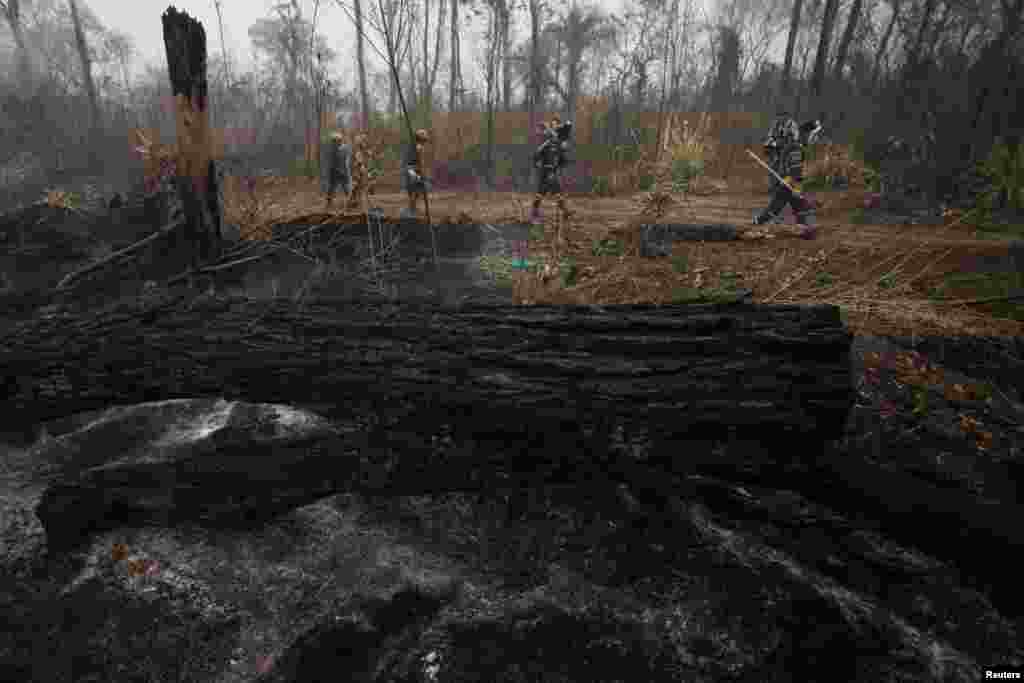 Los bomberos pasan por una zona forestal carbonizada mientras trabajan para enfriar el suelo después de un incendio forestal en Río Blanco, Bolivia. (REUTERS)