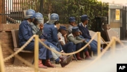 FILE: Zimbabwe riot police sit outside the hospital in Harare, Sept. 25, 2019, where the head of the Zimbabwe Hospital Doctors Association Dr. Peter Magombeyi is currently receiving medical care