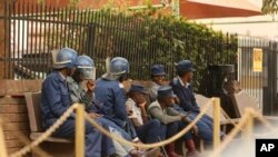 Zimbabwe riot police sit outside the hospital in Harare, Sept. 25, 2019, where the head of the Zimbabwe Hospital Doctors Association Dr. Peter Magombeyi is currently receiving medical care