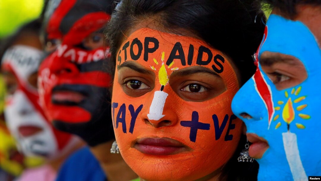 FILE - Students with their faces painted with messages pose during an HIV/AIDS awareness campaign to mark the International AIDS Candlelight Memorial, in Chandigarh, India, May 20, 2018. 