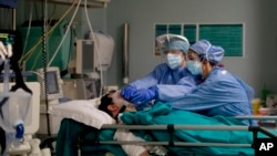 FILE - In this April 16, 2020 file photo, medical staff tend to a patient in the emergency COVID-19 ward at the San Carlo Hospital in Milan, Italy.