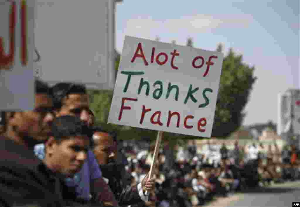 A Libyan man holds up a sign before Friday prayers in the eastern city of Ajdabiya, Libya, Friday, March 11, 2011. French President Nicolas Sarkozy faced increasing pressure from fellow leaders Friday who complained he was out of line to suddenly give a L