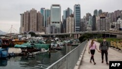 FILE - A couple (R) walks along the promenade on victoria harbour in Hong Kong on April 25, 2020. 