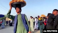 Vendors carry trays with food outside Kabul airport, Afghanistan, August 22, 2021 in this still image taken from video. 