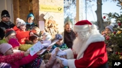 A man dressed as Santa Claus is welcomed by children during the opening of the most famous German Christmas mail office in the small village of Himmelpfort (Heaven's Door) north of Berlin, Germany, Nov. 14, 2019.