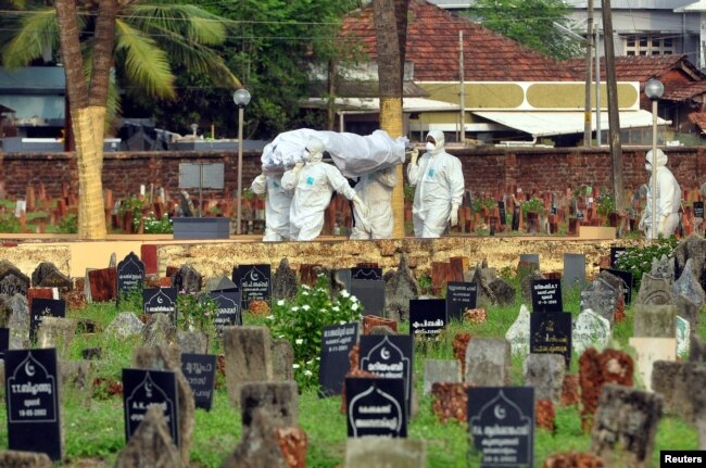 Dokter dan kerabat yang mengenakan APD membawa jenazah seorang korban yang terjangkit virus Nipah yang merusak otak, di Kozhikode, di India selatan, 24 Mei 2018. (Foto: Reuters)