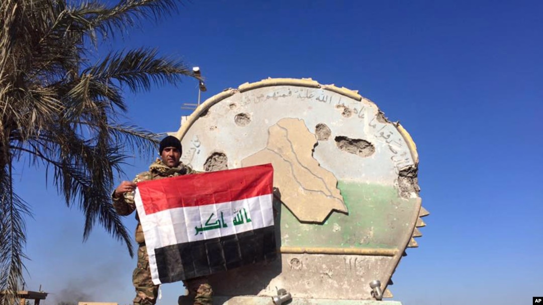 Seorang tentara Irak memegang bendera nasional di atas kompleks pemerintah di Ramadi tengah, Irak, 28 Desember 2015. 