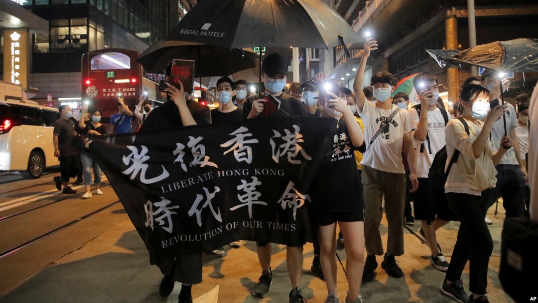 Para demonstran pro-demokrasi menunjukkan spanduk bertuliskan "Librate Hong Kong, Revolution of Our Time" menandai ulang tahun pertama demonstrasi massa menentang RUU ekstradisi yang sudah ditarik di Hong Kong, Selasa, 9 Juni 2020.