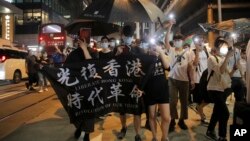 Para demonstran pro-demokrasi menunjukkan spanduk bertuliskan "Librate Hong Kong, Revolution of Our Time" menandai ulang tahun pertama demonstrasi massa menentang RUU ekstradisi yang sudah ditarik di Hong Kong, Selasa, 9 Juni 2020.