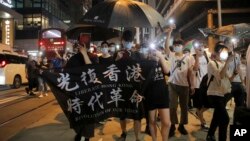 Para demonstran pro-demokrasi membentangkan spanduk bertuliskan "Bebaskan Hong Kong, Revolusi Sejarah Kita," dalam demo memperingati satu tahun unjuk rasa anti pemerintah di Hong Kong, Selasa, 9 Juni 2020. (Foto: AP)