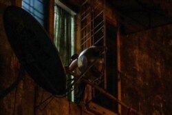 A metal basin is used by a resident to hit the window grill to make noise during a noise barrage campaign in Yangon, Myanmar, Tuesday, Feb. 2, 2021.