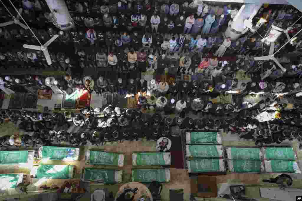 Palestinians pray by the bodies of 15 members of the Izzedine al-Qassam Brigades, the military wing of Hamas movement, who were killed in Israeli bombardment of the Gaza Strip, in Khan Younis.