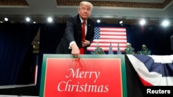 U.S. President Donald Trump points to a "Merry Christmas" placard on the stage as he arrives to deliver remarks on tax reform in St. Louis, Missouri, U.S. November 29, 2017. 