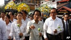 Chea Mony, center, president of the Free trade Union, and Sam Rainsy, foreground right, the head of the main opposition Cambodia National Rescue Party (CNRP), walk together during a march to mark the 10th anniversary in remembrance of Chea Vichea on his assassination, in Phnom Penh, Cambodia, Wednesday, Jan. 22, 2014. Chea Vichea, a former prominent leader of Free trade Union, was assassinated 10 years ago. (AP Photo/Heng Sinith)