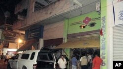 People look at a crime scene where three women were found brutally murdered at a beauty parlor in the resort city of Acapulco, April 23, 2011