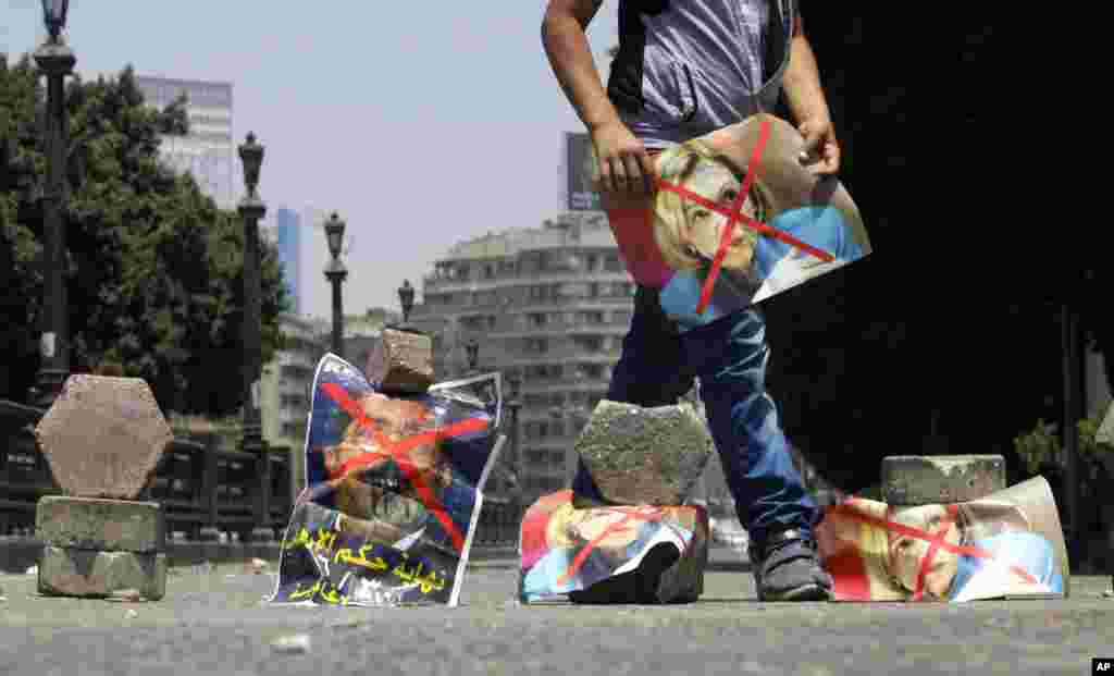 An Egyptian protester holds posters depicting U.S. Ambassador to Egypt Anne Patterson and President Mohamed Morsi at an entrance to Tahrir Square in Cairo, June 28, 2013. 