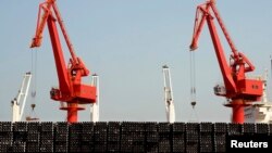 FILE - Piles of steel pipes to be exported are seen in front of cranes at a port in Lianyungang, Jiangsu province, March 7, 2015. 