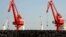 FILE - Piles of steel pipes to be exported are seen in front of cranes at a port in Lianyungang, Jiangsu province, March 7, 2015. 