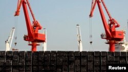 FILE - Piles of steel pipes to be exported are seen in front of cranes at a port in Lianyungang, Jiangsu province, March 7, 2015. 