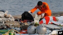 Anggota BASARNAS memeriksa serpihan badan pesawat Lion Air yang berserakan di pelabuhan Tanjung Priok, Jakarta, Senin (29/10). 