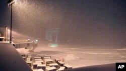 Airline baggage carts sit on the tarmac as crews prepare to remove snow at the Albany International Airport in Colonie, N.Y., Jan. 20, 2019. 