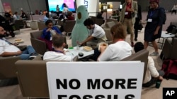 在迪拜举行的第28届联合国气候大会（COP 28）2023年12月12日在原定会期结束后进入加时段，一些与会者和场外观察人士正在吃午餐。（美联社）