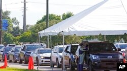 FILE - Cars line up at Miami Dade College North Campus' COVID-19 testing site, July 29, 2021, in Miami. Hospital admissions of coronavirus patients continue to soar in Florida.