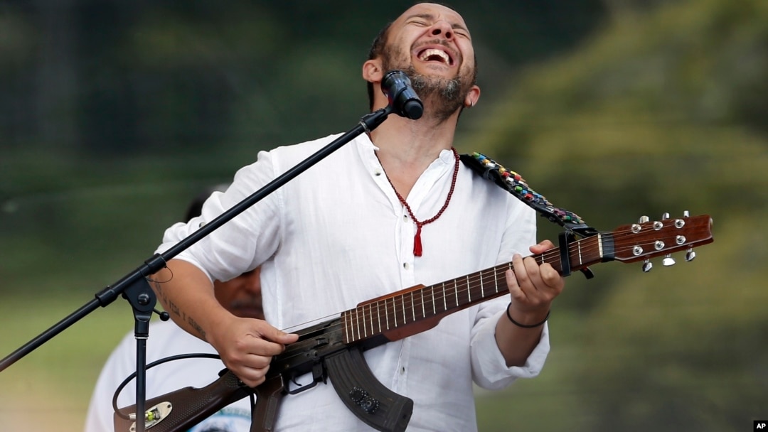 ARCHIVO - El músico colombiano César López toca su guitarra, que fusionó con un arma real y la llama "Escopetarra". Visto el 27 de junio de 2017, en acto para conmemorar la finalización del proceso de desarme de los rebeldes de las FARC, en Buenavista, Colombia.