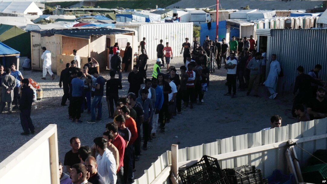 Para migran antri untuk memperoleh bantuan makanan di kamp sementara di Calais, Perancis utara. (AP Photo/Michel Spingler).