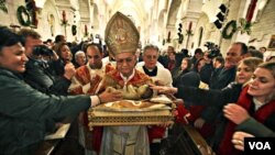 Uskup agung Yerusalem membawa patung bayi Yesus setelah upacara Misa Natal di Bethlehem, 25 Desember 2010.