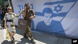 An Israeli soldier and a woman walk past a protest tent near the Prime Minister's residence, in Jerusalem, calling for the release of captured Israeli soldier Gilad Schalit, June 24, 2011.