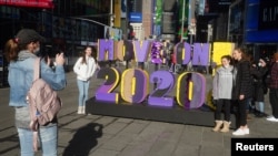 People take a selfie in front of a "Move on 2020!" sign in Times Square amid the coronavirus disease (COVID-19) pandemic in the Manhattan borough of New York City, New York, U.S., December 28, 2020. REUTERS/Carlo Allegri