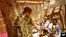 FILE - Malagasy women and children wait in the shade at a makeshift village clinic in Antanetikely, Madagascar, Oct. 23, 2007.